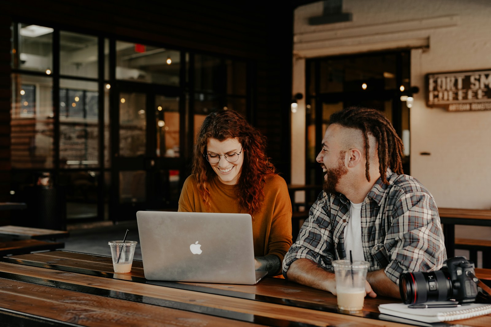 A man and woman in casual clothes working together at a café table; illustrative stock photography